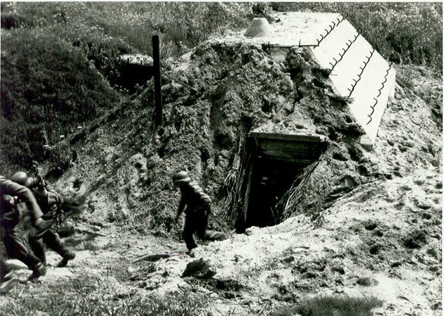 zwartwitfoto van Duitse soldaten die in mei 1940 een groepsschuilplaats type-p met gronddekking onderzoeken. Exacte locatie onbekend. Bron: Kenniscentrum Waterlinies. 