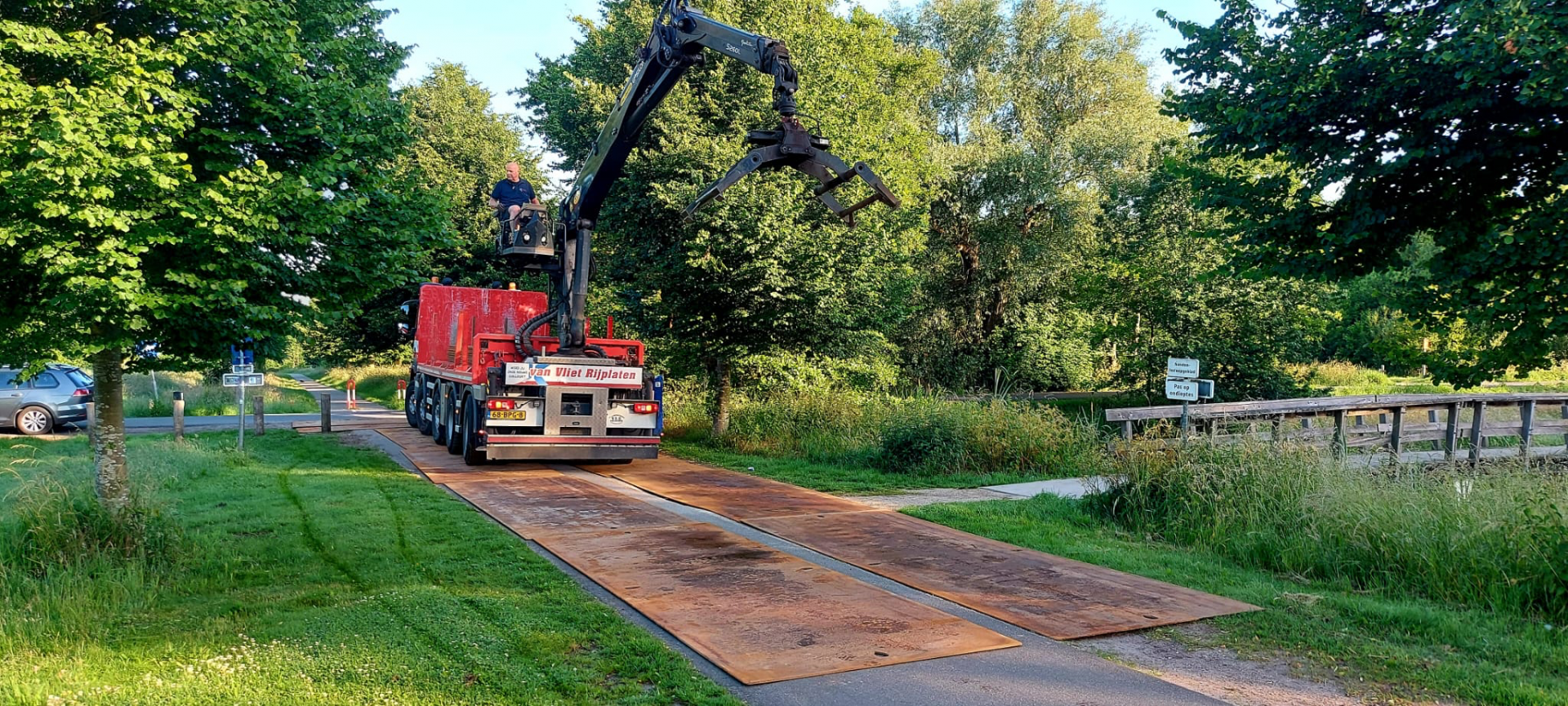 voorbereidingen voor de aanleg van de pumptrack met een grijpmachine op rijplaten in Noorderpark Ruigenhoek