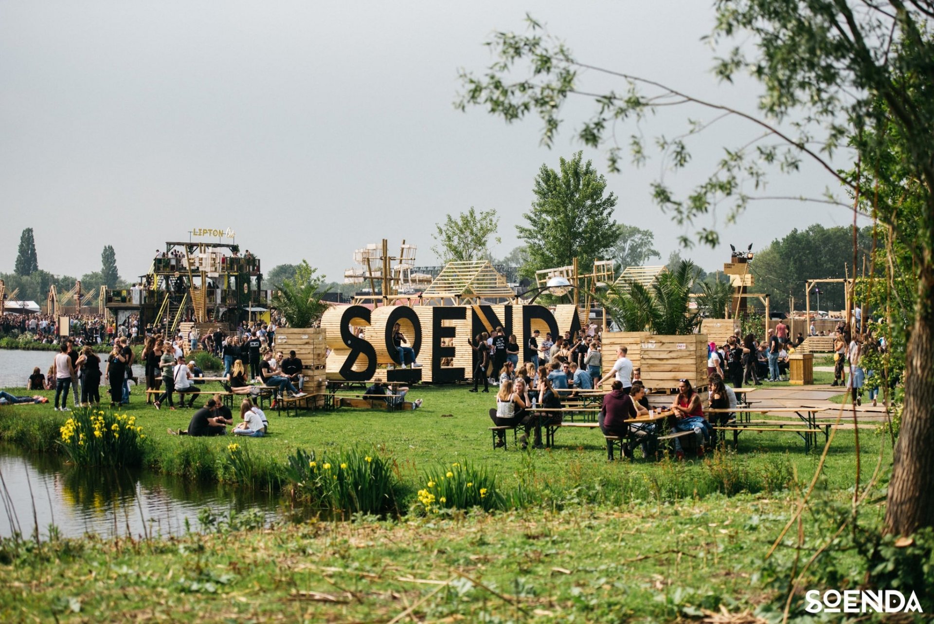Bezoekers aan Soenda Festival in Noorderpark Ruigenhoek met heel groot de houten letters 'SOENDA' in het gras