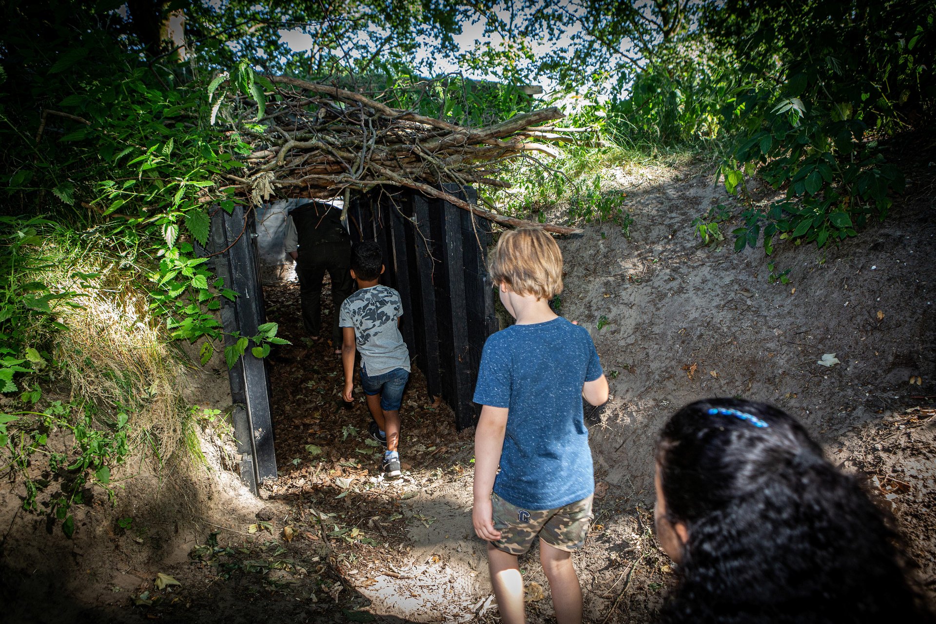 Kinderen rennen door een tunnel begroeid met planten en bomen