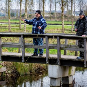 Twee mannen staan te vissen op een brug. 