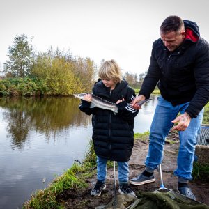 vader en zoon houden een grote vis vast op de steiger in Noorderpark Ruigenhoek